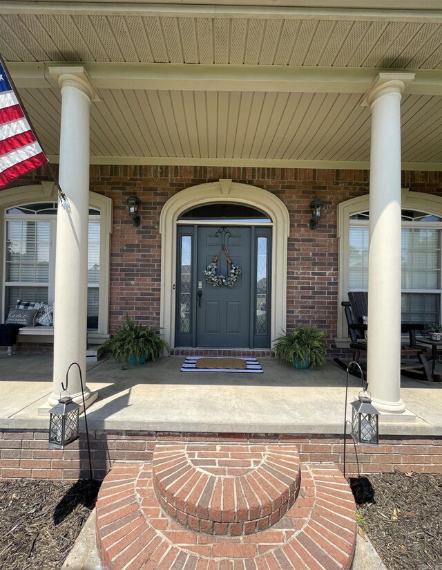 property entrance with covered porch and brick siding