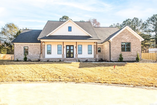 modern farmhouse style home featuring french doors, brick siding, roof with shingles, and fence