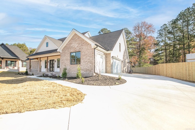 modern inspired farmhouse with covered porch, a garage, brick siding, fence, and concrete driveway