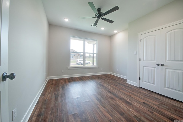 unfurnished bedroom featuring ceiling fan, a closet, and dark wood-type flooring