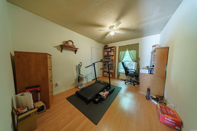 workout area featuring ceiling fan, a textured ceiling, and wood-type flooring