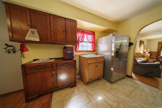 kitchen featuring stainless steel fridge with ice dispenser, light hardwood / wood-style floors, and a textured ceiling