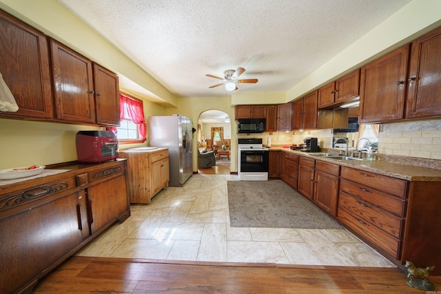 kitchen featuring backsplash, sink, white range with electric cooktop, light wood-type flooring, and stainless steel fridge