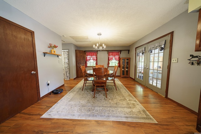 dining area with a wealth of natural light, french doors, light hardwood / wood-style floors, and a chandelier