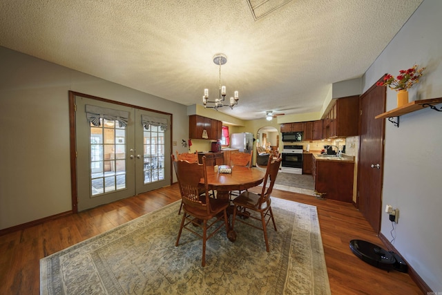 dining room featuring hardwood / wood-style floors, sink, french doors, ceiling fan with notable chandelier, and a textured ceiling