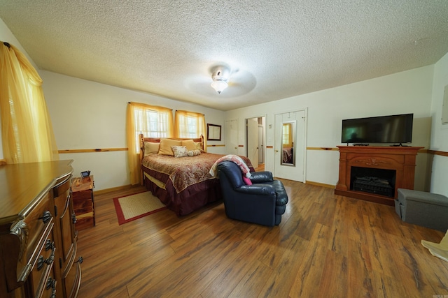 bedroom with ceiling fan, dark wood-type flooring, and a textured ceiling