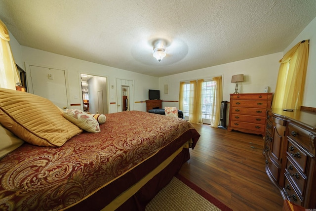 bedroom with a textured ceiling, ceiling fan, and dark hardwood / wood-style floors