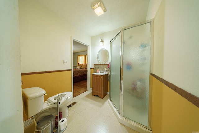 bathroom featuring vanity, toilet, tile patterned floors, and a shower with shower door