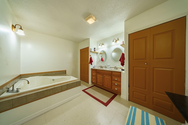 bathroom featuring a bath, tile patterned flooring, a textured ceiling, and vanity