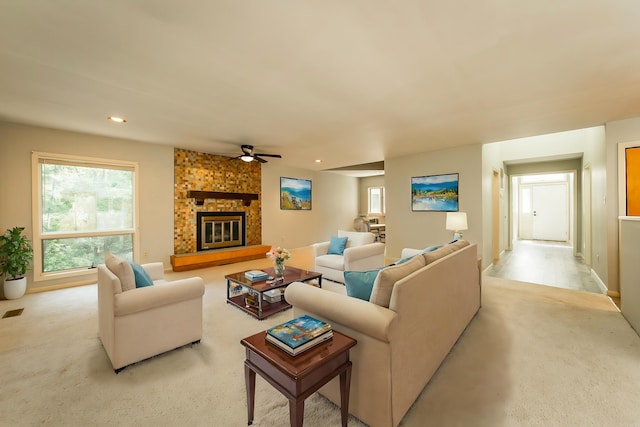 living room with ceiling fan, light colored carpet, and a fireplace