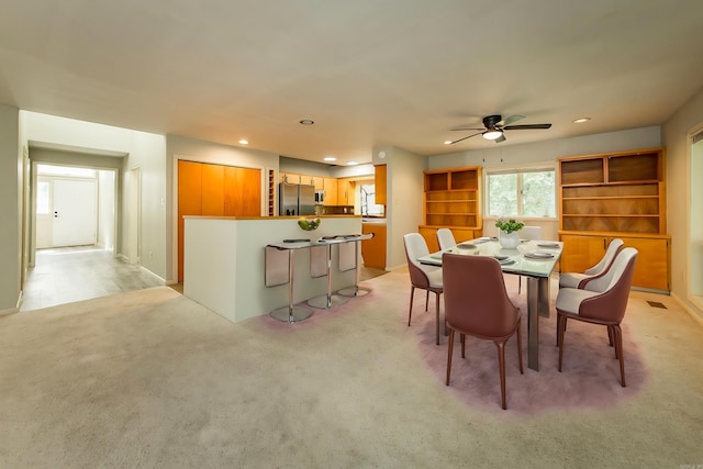 dining room with ceiling fan, light carpet, and built in features