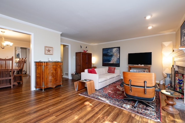 living room with a fireplace, dark wood-type flooring, a chandelier, and ornamental molding