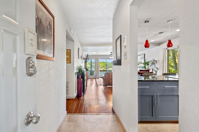 corridor featuring a textured ceiling and light tile patterned floors