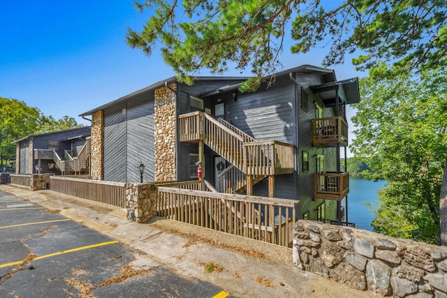 view of property exterior with stairs, uncovered parking, and a water view