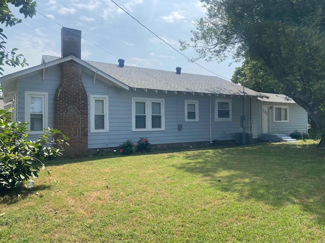 rear view of house featuring central AC and a yard