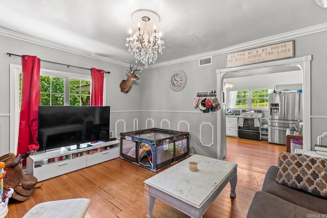 living room featuring a notable chandelier, hardwood / wood-style floors, and ornamental molding