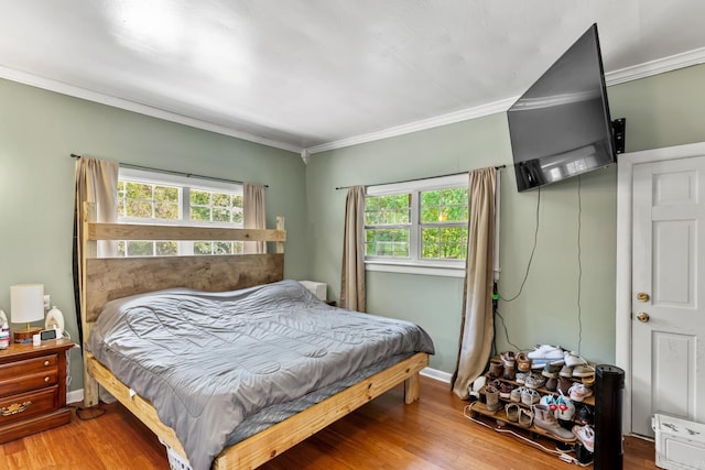 bedroom featuring ornamental molding and wood finished floors