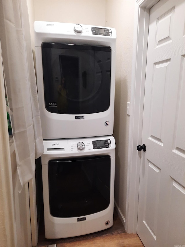 laundry room featuring stacked washer and clothes dryer and light hardwood / wood-style flooring