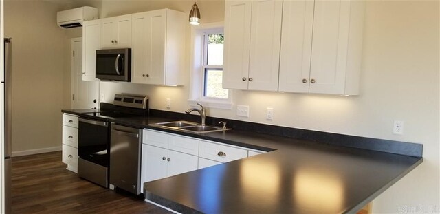 kitchen with sink, a wall unit AC, appliances with stainless steel finishes, dark hardwood / wood-style floors, and white cabinets