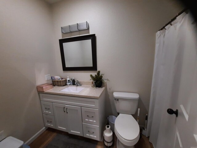 bathroom featuring wood-type flooring, toilet, and vanity