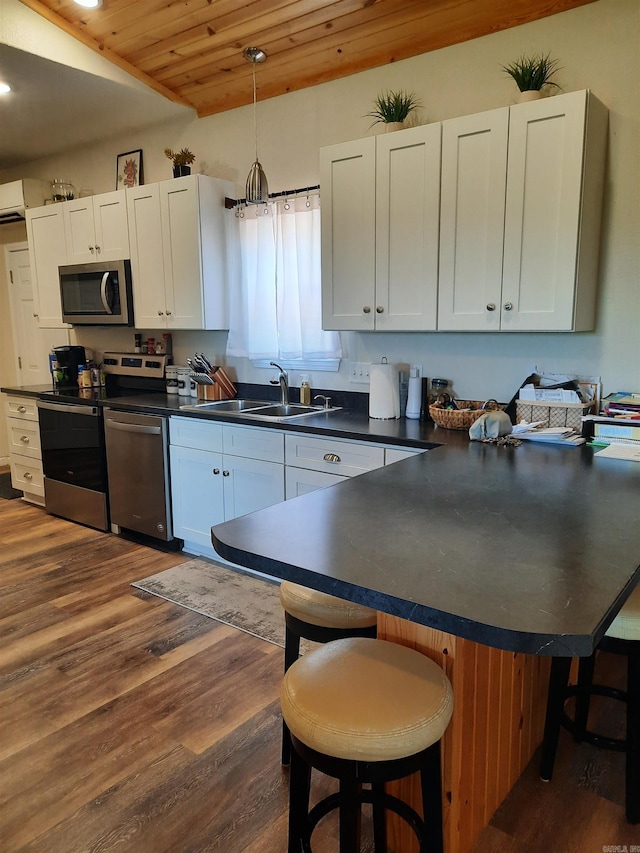 kitchen featuring a kitchen bar, sink, appliances with stainless steel finishes, wooden ceiling, and hanging light fixtures