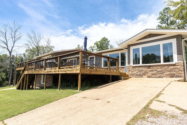 rear view of house with stone siding, a lawn, and a deck