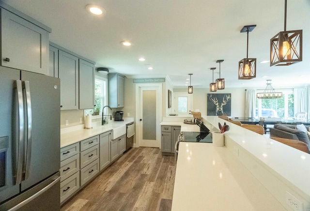 kitchen featuring stainless steel appliances, decorative light fixtures, hardwood / wood-style flooring, sink, and gray cabinets