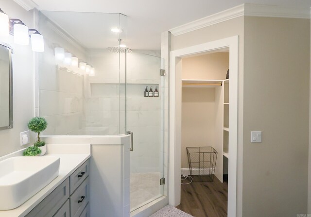 bathroom featuring crown molding, wood-type flooring, vanity, and a shower with shower door