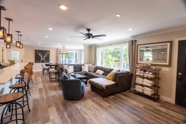 living room featuring hardwood / wood-style floors, ceiling fan with notable chandelier, crown molding, and a wealth of natural light