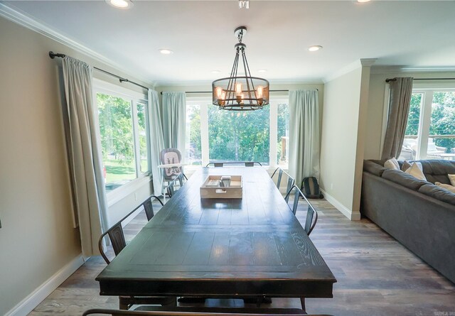 dining room featuring hardwood / wood-style flooring, a notable chandelier, plenty of natural light, and ornamental molding