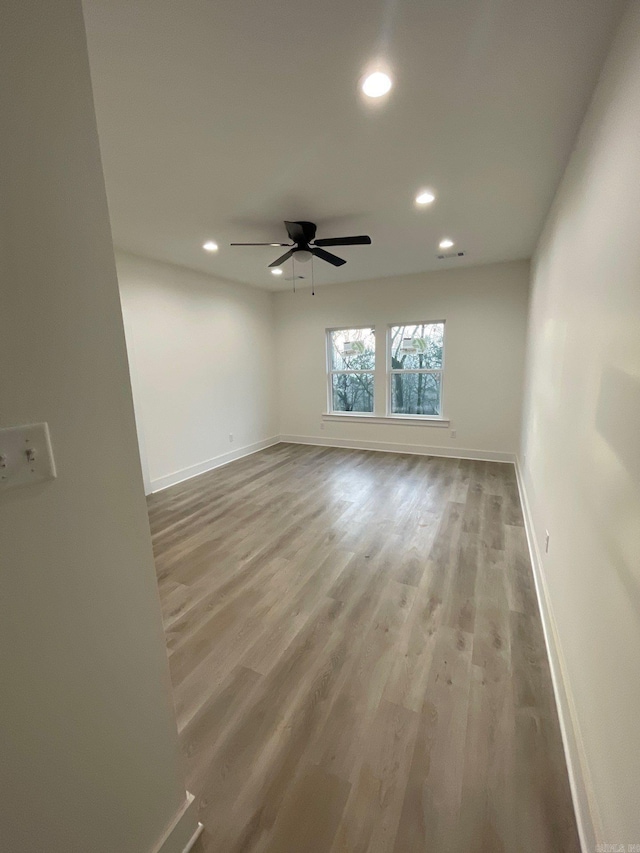 spare room with ceiling fan and light wood-type flooring