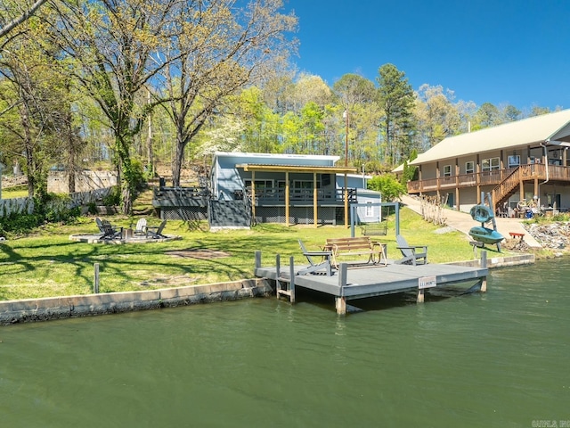 dock area featuring an outdoor fire pit, a deck with water view, a lawn, and stairs