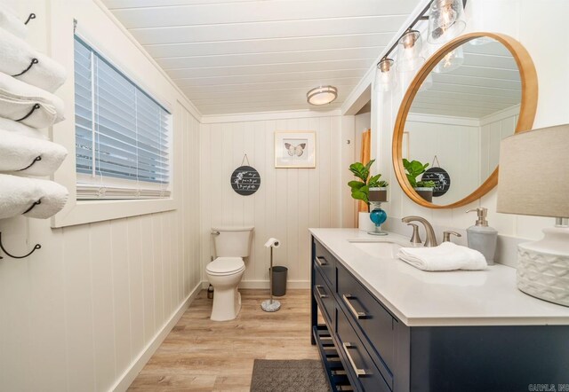 bathroom featuring toilet, hardwood / wood-style floors, ornamental molding, and vanity