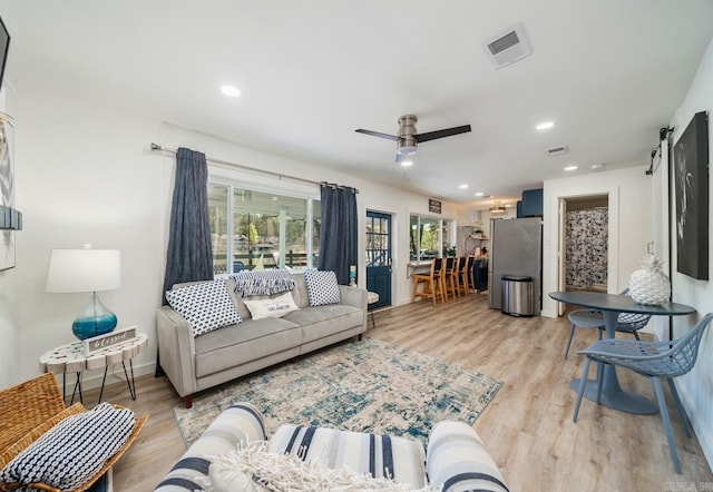 living area featuring ceiling fan, a barn door, light wood-style flooring, recessed lighting, and visible vents