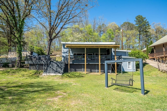 back of property with a deck, a lawn, and stairs