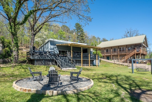 rear view of house with an outdoor fire pit, stairs, a deck, and a lawn