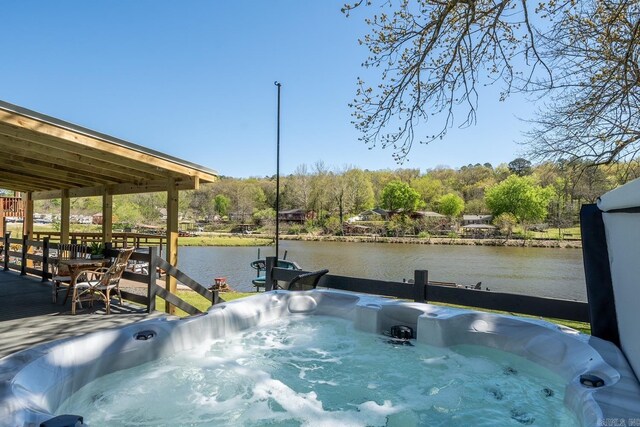 view of pool with a hot tub and a water view