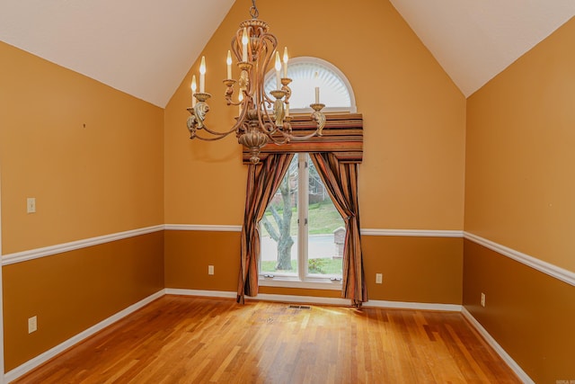 empty room featuring vaulted ceiling, a chandelier, and wood-type flooring