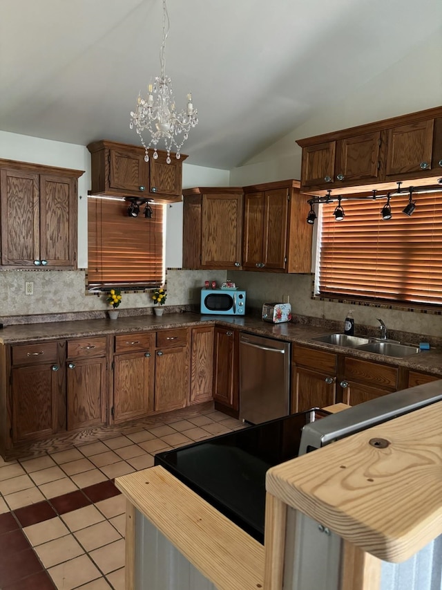 kitchen with stainless steel dishwasher, sink, a chandelier, lofted ceiling, and light tile patterned flooring