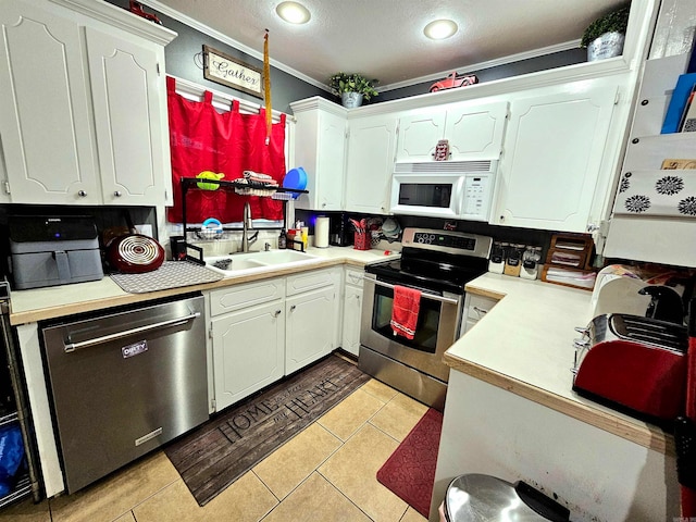 kitchen featuring stainless steel appliances, ornamental molding, light tile patterned floors, and white cabinets