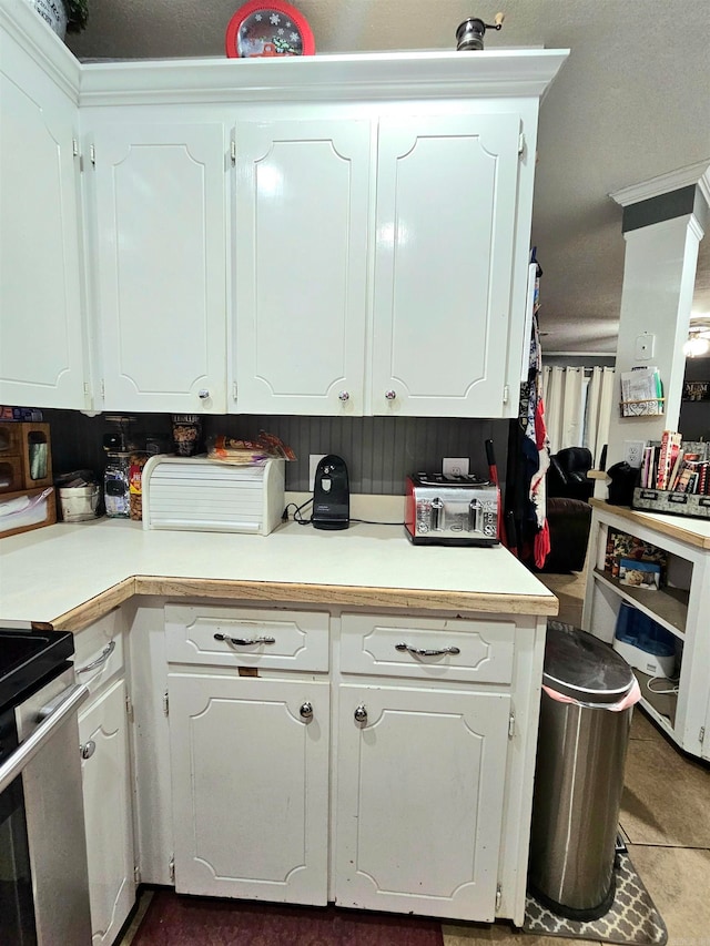 kitchen with tile patterned flooring, stainless steel stove, and white cabinetry