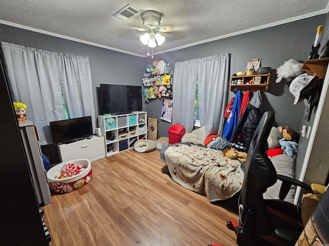 interior space with a textured ceiling, ceiling fan, ornamental molding, and hardwood / wood-style floors