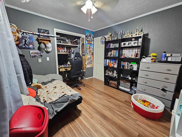 bedroom featuring hardwood / wood-style flooring, a closet, ceiling fan, ornamental molding, and a textured ceiling