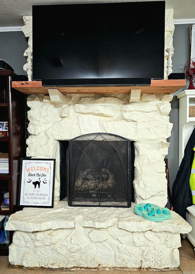 room details with tile patterned flooring, ornamental molding, and a stone fireplace