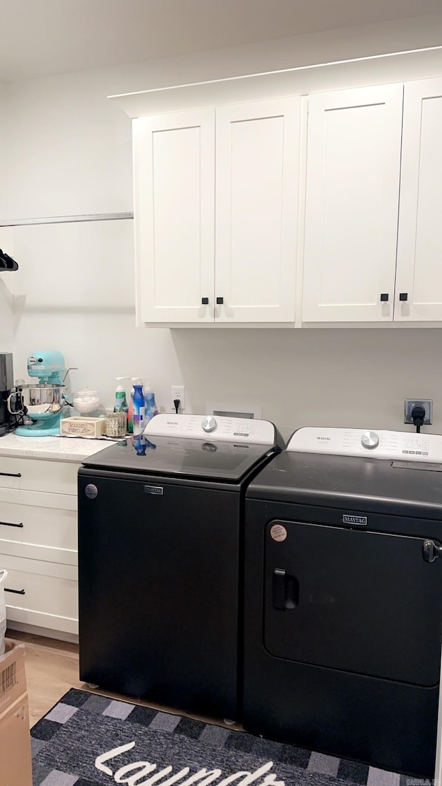 washroom featuring light wood-type flooring, cabinet space, and washer and dryer