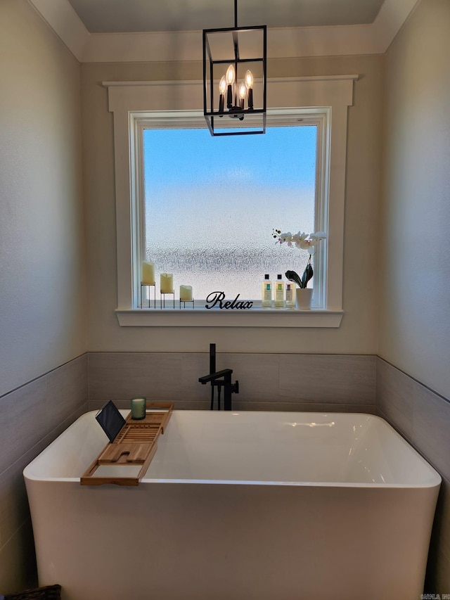 bathroom featuring a freestanding bath, a wealth of natural light, and a notable chandelier