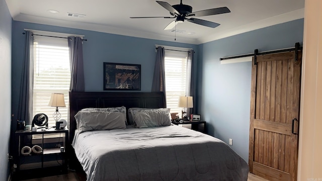 bedroom featuring a ceiling fan, multiple windows, crown molding, and a barn door