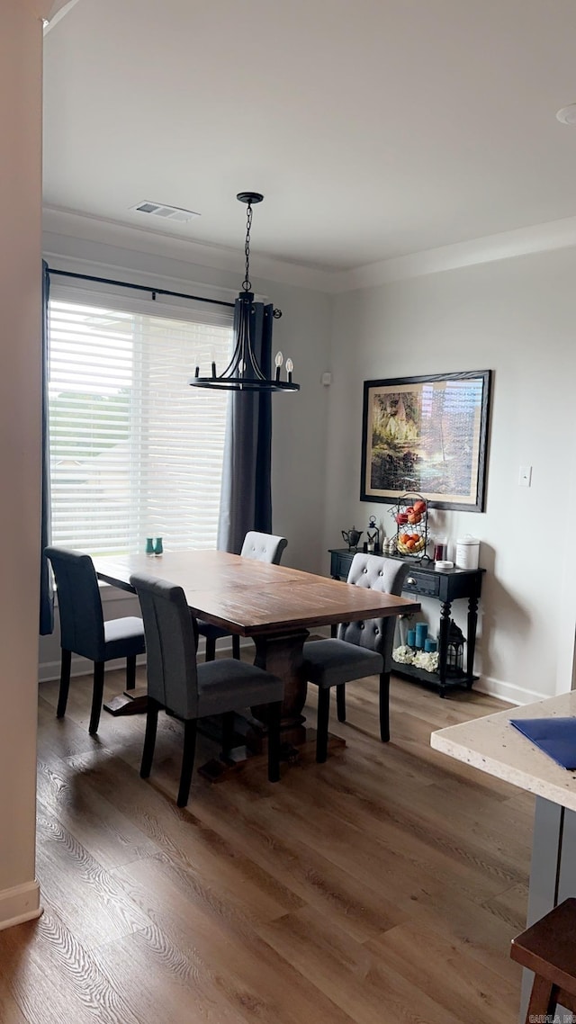 dining space featuring baseboards, crown molding, visible vents, and wood finished floors