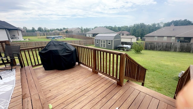 wooden deck with a storage shed, an outbuilding, a grill, and a residential view