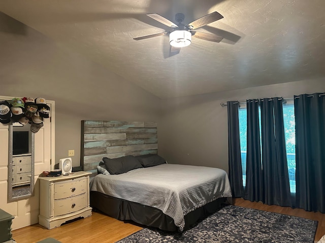 bedroom featuring lofted ceiling, ceiling fan, hardwood / wood-style flooring, and a textured ceiling